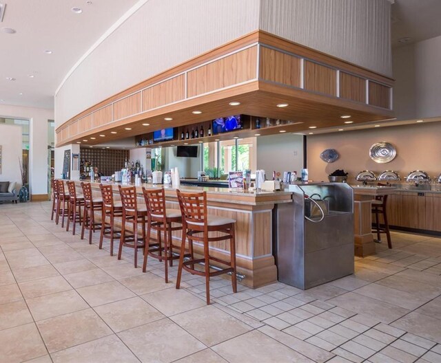 bar featuring light tile patterned floors and a high ceiling