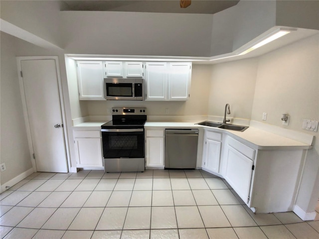 kitchen with appliances with stainless steel finishes, light tile patterned floors, white cabinetry, and sink