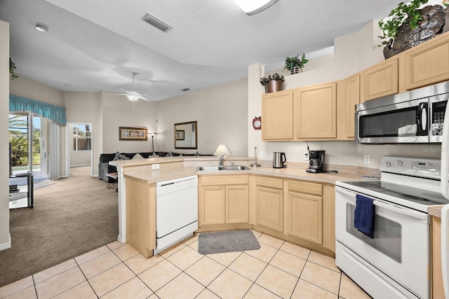 kitchen featuring kitchen peninsula, light tile patterned floors, white appliances, and sink