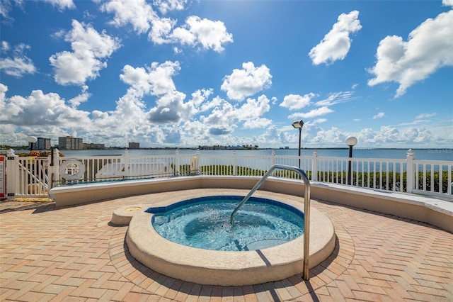 view of pool featuring a community hot tub, a water view, and a patio area