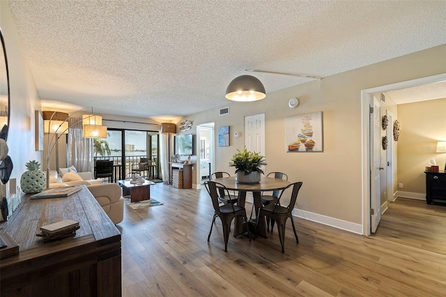 dining room featuring hardwood / wood-style flooring and a textured ceiling