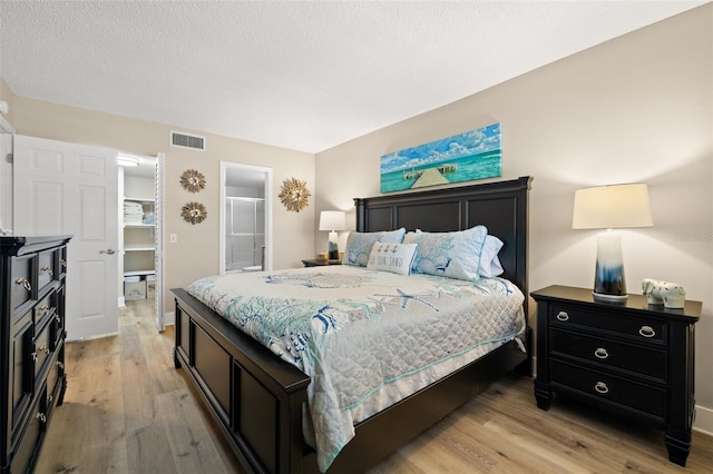 bedroom with a textured ceiling and light wood-type flooring