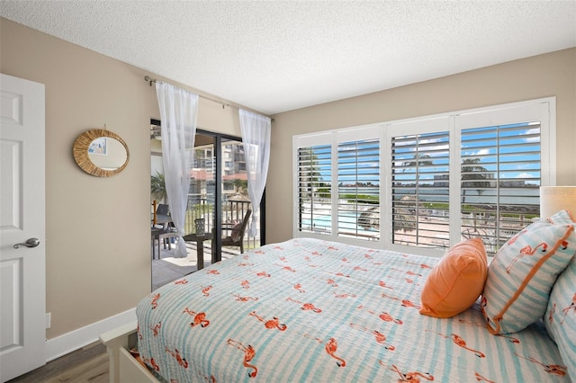 bedroom with dark hardwood / wood-style flooring, a textured ceiling, and access to outside