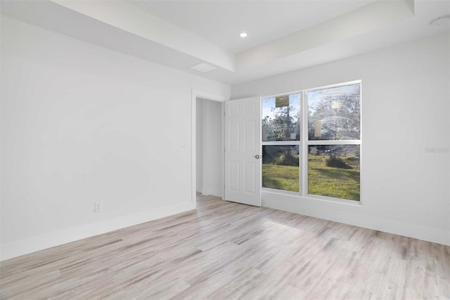 unfurnished room with a tray ceiling and light hardwood / wood-style flooring