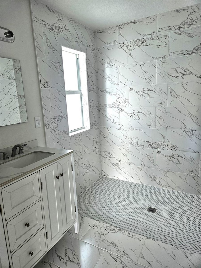 bathroom featuring tiled shower, vanity, and a textured ceiling