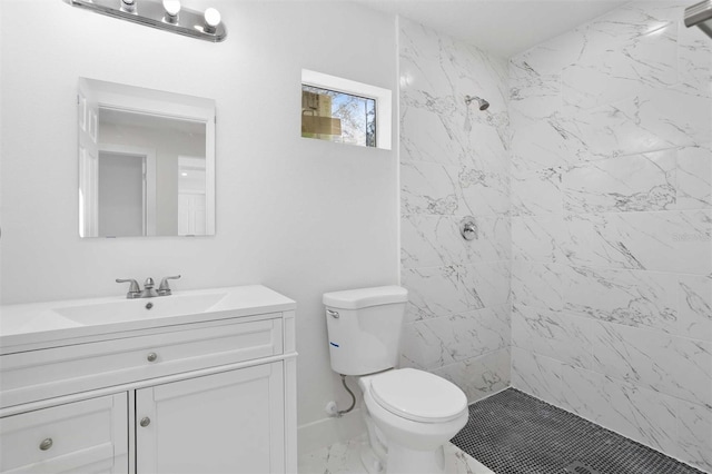 bathroom featuring a tile shower, vanity, and toilet