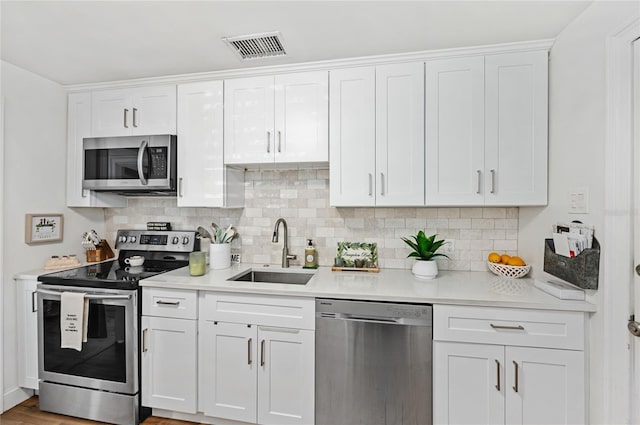 kitchen with appliances with stainless steel finishes, tasteful backsplash, white cabinetry, and sink