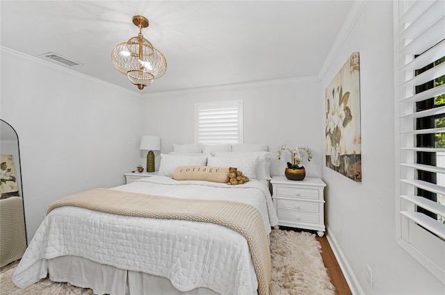 bedroom featuring hardwood / wood-style flooring, ornamental molding, and a chandelier