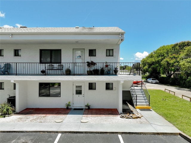 exterior space with a balcony, stairway, and stucco siding