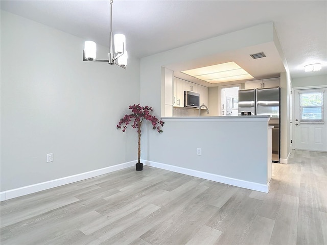 interior space featuring baseboards, an inviting chandelier, visible vents, and light wood-style floors