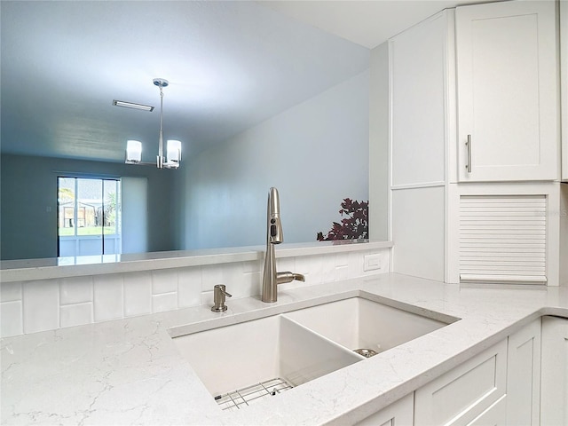 kitchen featuring sink, pendant lighting, and white cabinetry