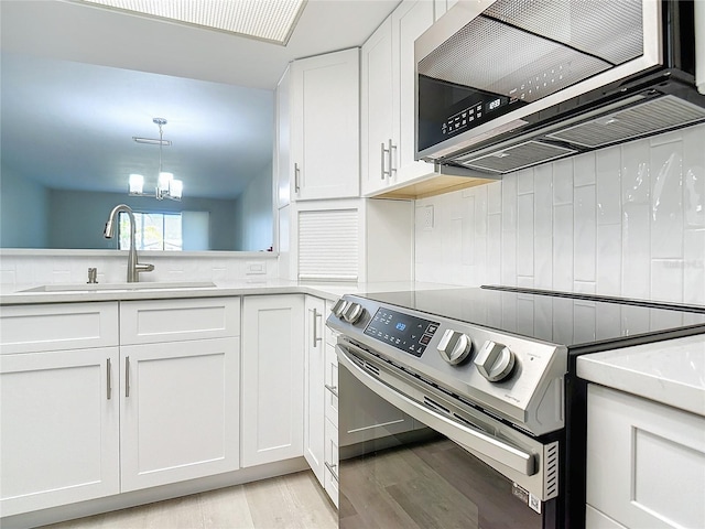 kitchen featuring stainless steel appliances, a sink, white cabinets, light countertops, and pendant lighting