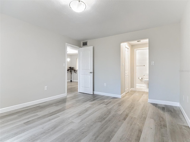 unfurnished bedroom with baseboards, a textured ceiling, visible vents, and light wood-style floors