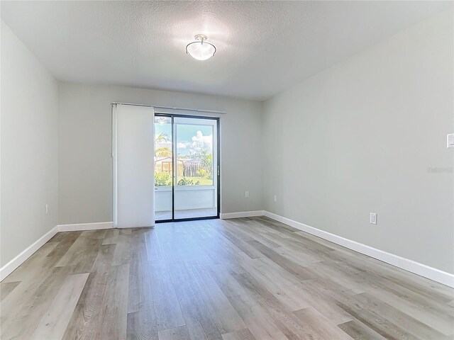 unfurnished room with light hardwood / wood-style flooring and a textured ceiling