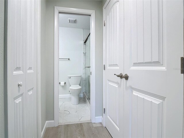 bathroom with toilet, a shower with door, and hardwood / wood-style flooring