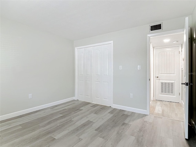 unfurnished bedroom featuring a closet, light wood-type flooring, visible vents, and baseboards