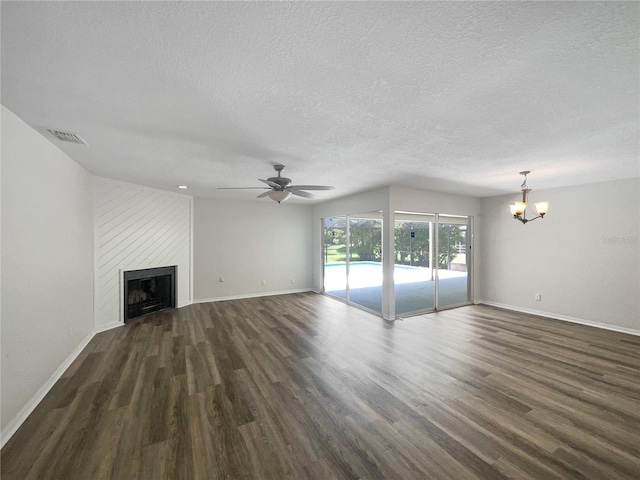 unfurnished living room featuring a fireplace, ceiling fan with notable chandelier, a textured ceiling, and dark hardwood / wood-style flooring