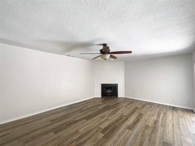 unfurnished living room featuring a textured ceiling, dark hardwood / wood-style floors, ceiling fan, and a large fireplace