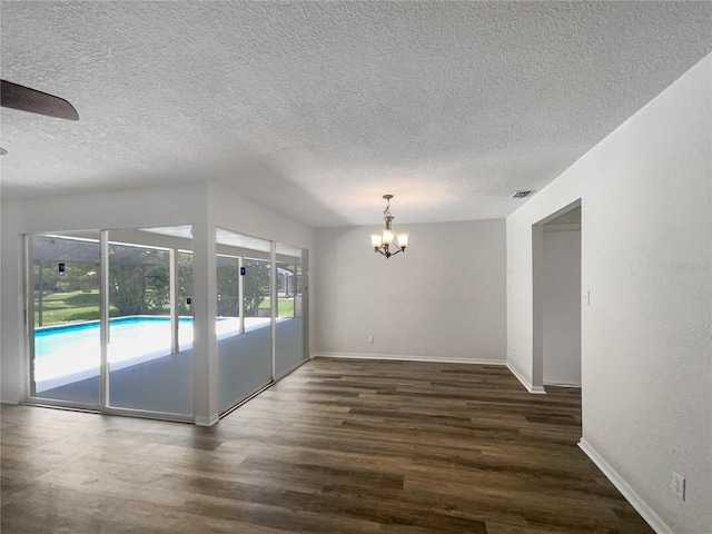 empty room featuring ceiling fan with notable chandelier, dark wood-type flooring, and plenty of natural light