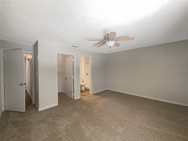 unfurnished bedroom featuring a spacious closet, carpet floors, a closet, ceiling fan, and ensuite bathroom