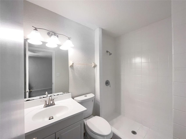 bathroom featuring tiled shower, toilet, and vanity