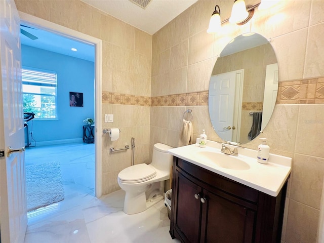 9060 Heritage Bay Cir, Orlando, FL 32836 - bathroom with tile walls, marble finish floor, toilet, and vanity