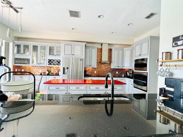 9060 Heritage Bay Cir, Orlando, FL 32836 - kitchen featuring visible vents, wall chimney exhaust hood, a sink, and stainless steel refrigerator with ice dispenser