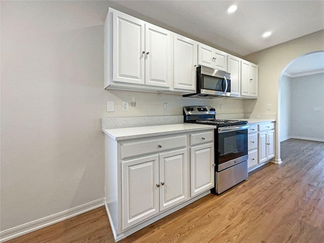 3444 97th Ln E, Palmetto, FL 34221 - kitchen featuring stainless steel appliances, arched walkways, light wood finished floors, white cabinetry, and light countertops