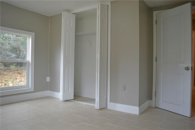 unfurnished bedroom with light tile patterned flooring and a closet