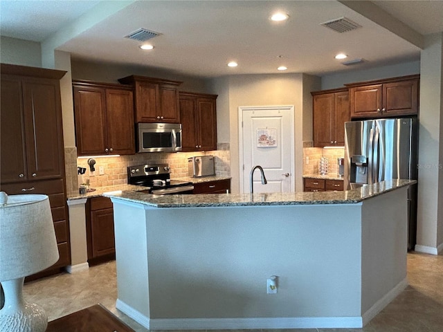 kitchen with stone countertops, a kitchen island with sink, recessed lighting, visible vents, and appliances with stainless steel finishes