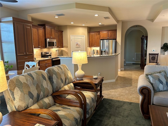 living room featuring arched walkways, baseboards, visible vents, and recessed lighting