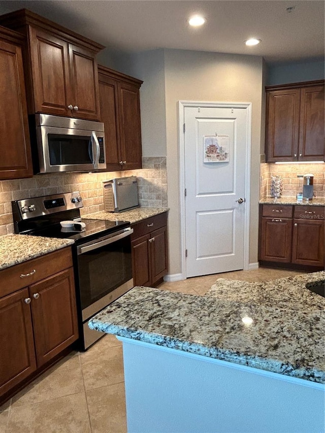 kitchen featuring light tile patterned floors, tasteful backsplash, appliances with stainless steel finishes, light stone countertops, and recessed lighting