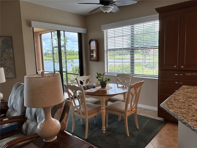 dining room with light tile patterned floors, a ceiling fan, baseboards, and a wealth of natural light