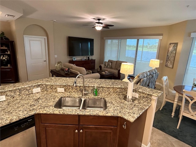 kitchen featuring open floor plan, stainless steel dishwasher, a sink, and light stone countertops