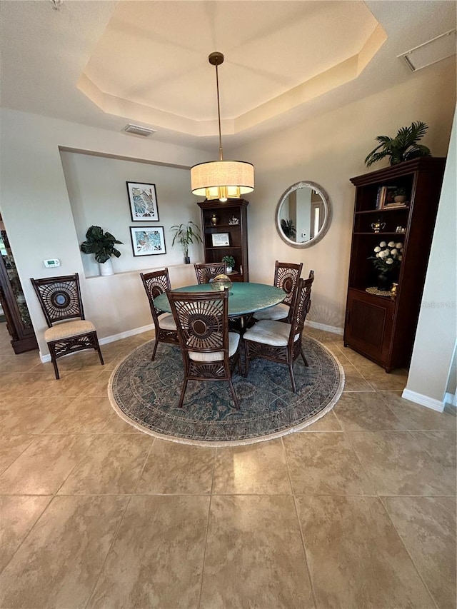 dining space featuring a tray ceiling, visible vents, and baseboards