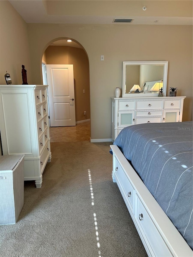 bedroom with arched walkways, visible vents, and baseboards