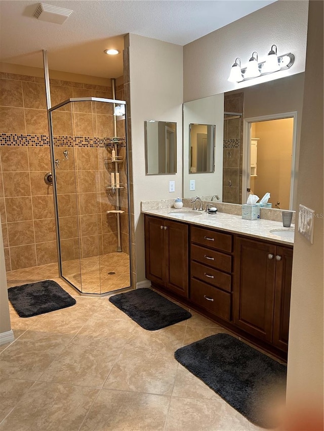 full bathroom featuring double vanity, a shower stall, visible vents, and a sink