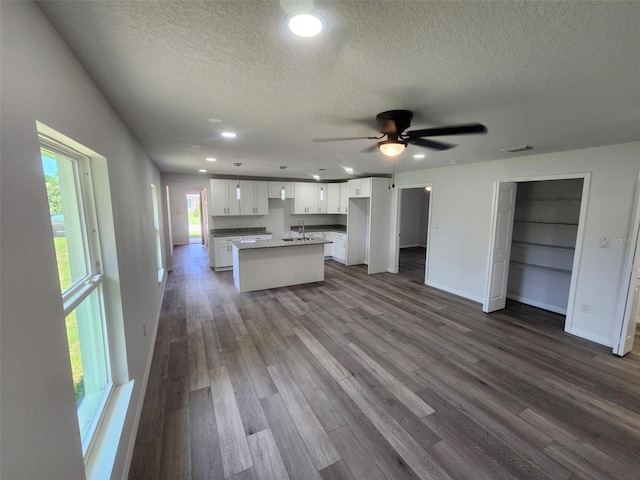 kitchen featuring a center island with sink, a sink, dark wood finished floors, open floor plan, and white cabinets
