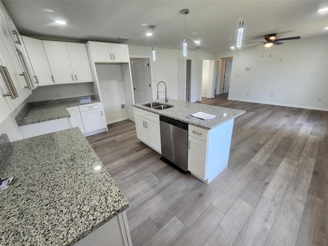 kitchen featuring a ceiling fan, a center island with sink, a sink, light wood-style floors, and dishwasher