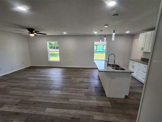 kitchen with decorative light fixtures, dark hardwood / wood-style floors, sink, a kitchen island with sink, and ceiling fan