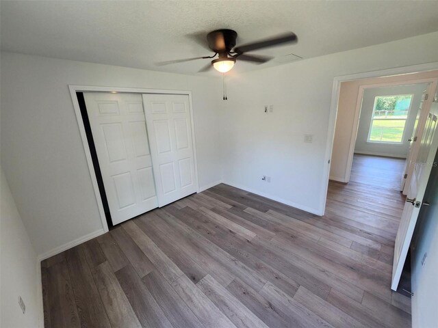 unfurnished bedroom featuring hardwood / wood-style floors, a closet, and ceiling fan