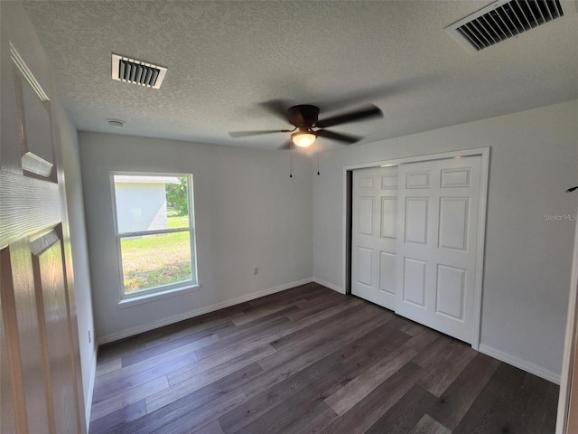 unfurnished bedroom featuring ceiling fan, a closet, a textured ceiling, and dark hardwood / wood-style floors