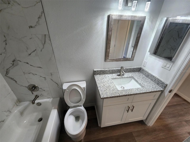 full bathroom with toilet, tiled shower / bath, hardwood / wood-style flooring, and vanity