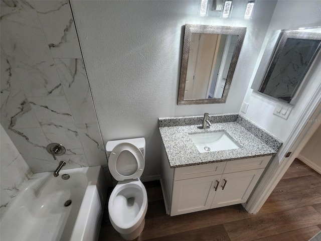 full bath with toilet, wood finished floors, shower / bath combination, vanity, and a textured wall