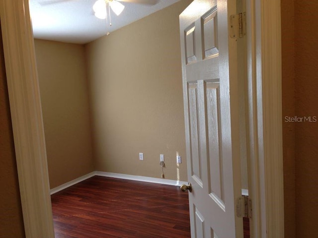 unfurnished room featuring baseboards, dark wood finished floors, and a ceiling fan