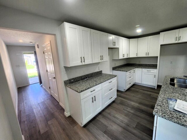 kitchen featuring a textured ceiling, white cabinetry, dark stone counters, and dark hardwood / wood-style floors