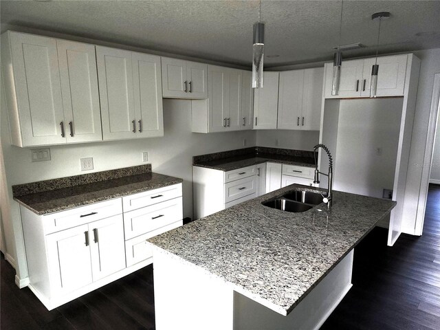 kitchen with a kitchen island with sink, sink, and hanging light fixtures