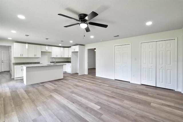 kitchen featuring white cabinetry, a center island, ceiling fan, and light hardwood / wood-style flooring