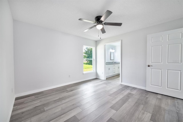 unfurnished bedroom with ceiling fan, a textured ceiling, light hardwood / wood-style flooring, and ensuite bath