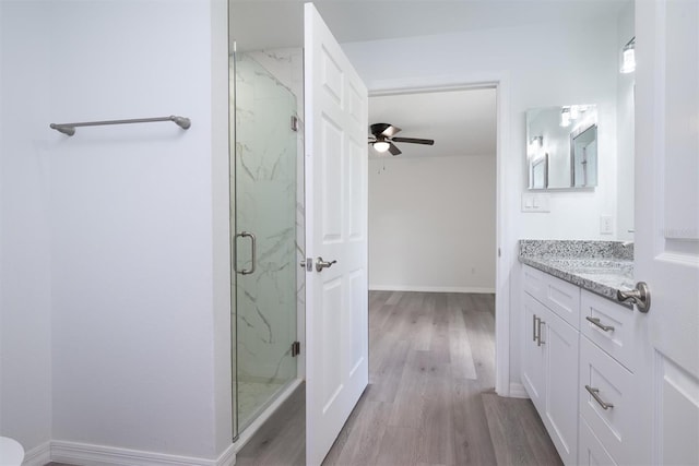 bathroom with wood-type flooring, vanity, ceiling fan, and a shower with door